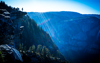 scenic view of mountain range with a person on a cliff looking out